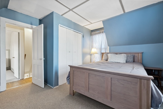 carpeted bedroom featuring vaulted ceiling and a closet