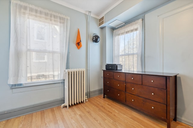 bedroom with radiator heating unit, light wood-type flooring, and baseboards