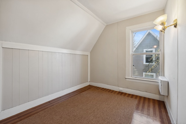 additional living space with a chandelier, vaulted ceiling, and wood finished floors