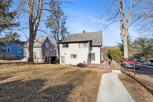 exterior space featuring a yard, a chimney, fence private yard, and roof with shingles