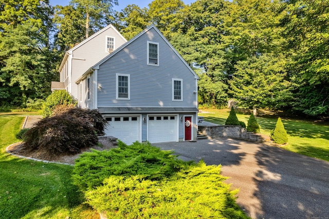 view of home's exterior featuring a garage, driveway, and a lawn