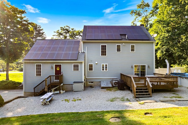 back of property featuring solar panels, a wooden deck, and fence