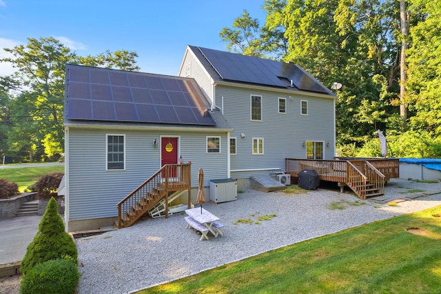 rear view of property featuring roof mounted solar panels, metal roof, and a wooden deck