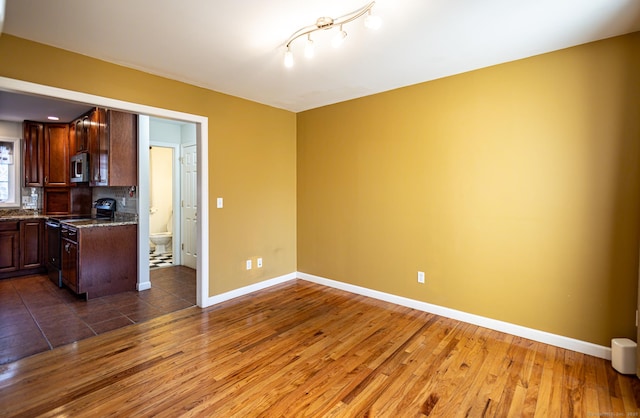 kitchen featuring dark wood-style flooring, range with electric cooktop, baseboards, decorative backsplash, and stainless steel microwave