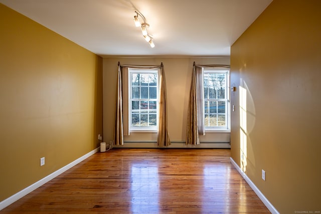 entryway with rail lighting, a baseboard radiator, baseboards, and wood finished floors