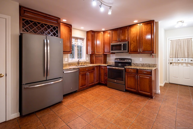 kitchen featuring light tile patterned floors, recessed lighting, stainless steel appliances, a sink, and light stone countertops