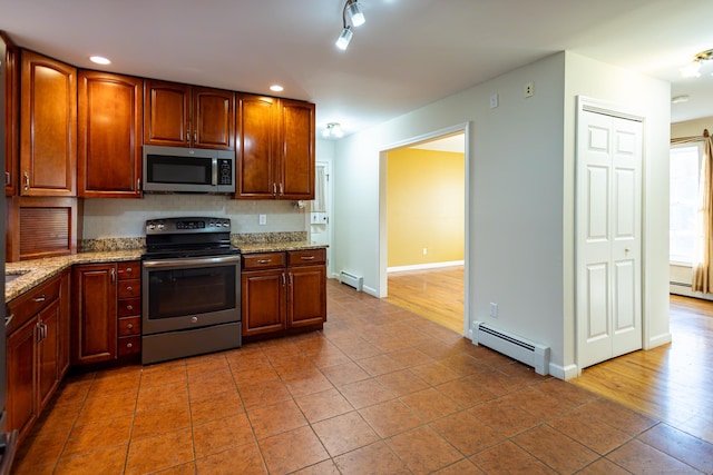 kitchen featuring stainless steel appliances, tasteful backsplash, baseboard heating, and light stone countertops