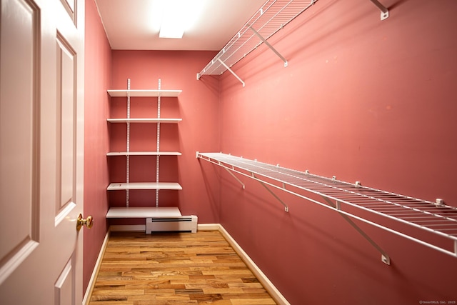 walk in closet with light wood-style flooring and baseboard heating