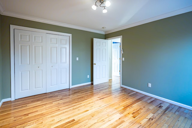 unfurnished bedroom featuring light wood-style floors, baseboards, ornamental molding, and a closet