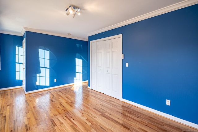 unfurnished bedroom featuring baseboards, a closet, ornamental molding, and hardwood / wood-style floors