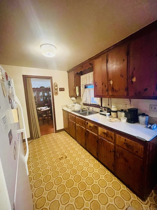 kitchen with light countertops, freestanding refrigerator, and a sink