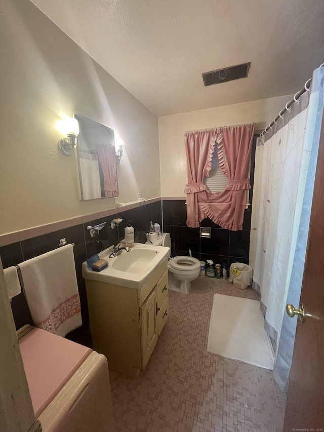 full bathroom with tile walls, toilet, wainscoting, a shower with curtain, and vanity