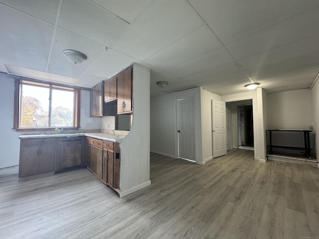 kitchen featuring a paneled ceiling, light countertops, light wood-style flooring, a baseboard heating unit, and baseboards