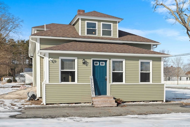 bungalow-style home with entry steps, roof with shingles, and a chimney