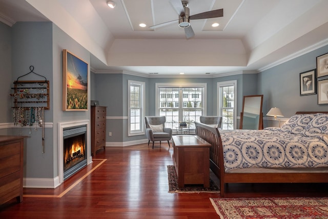 bedroom with a fireplace with flush hearth, a raised ceiling, baseboards, and wood finished floors