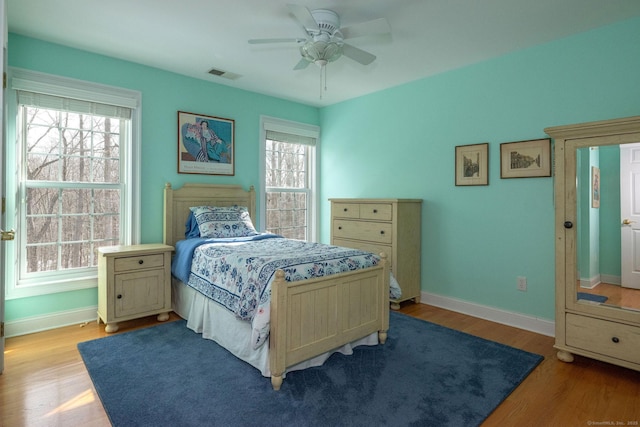 bedroom featuring light wood finished floors, a ceiling fan, visible vents, and baseboards