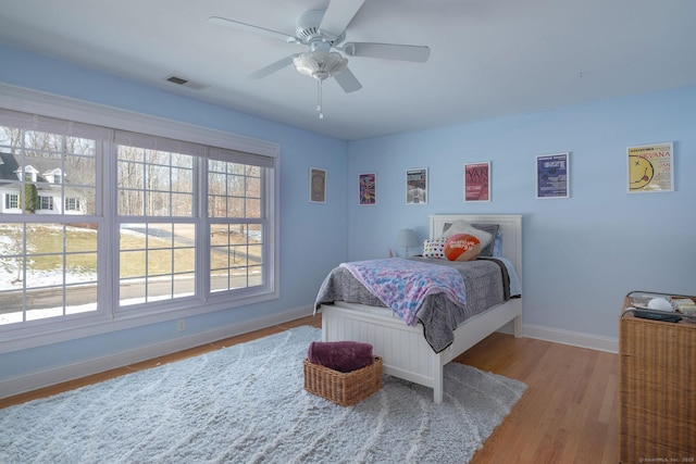 bedroom featuring ceiling fan, wood finished floors, visible vents, and baseboards