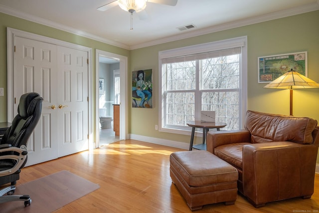 office with visible vents, baseboards, a ceiling fan, light wood-style flooring, and ornamental molding