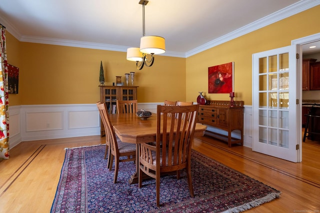 dining room with ornamental molding, wainscoting, and wood finished floors