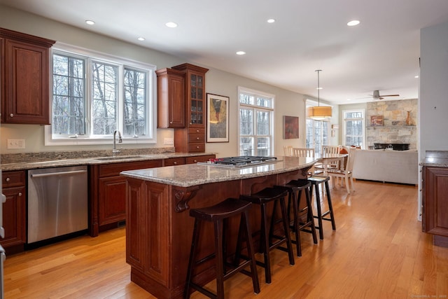 kitchen with light wood-style flooring, stainless steel appliances, a kitchen island, a sink, and a kitchen breakfast bar