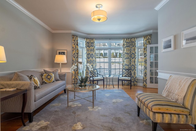 living area featuring ornamental molding, baseboards, and wood finished floors