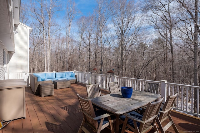 wooden deck with outdoor dining area, outdoor lounge area, and a view of trees