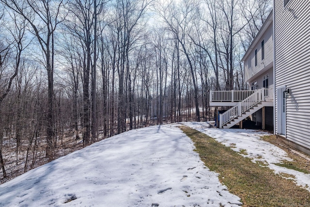 snowy yard with a deck and stairs