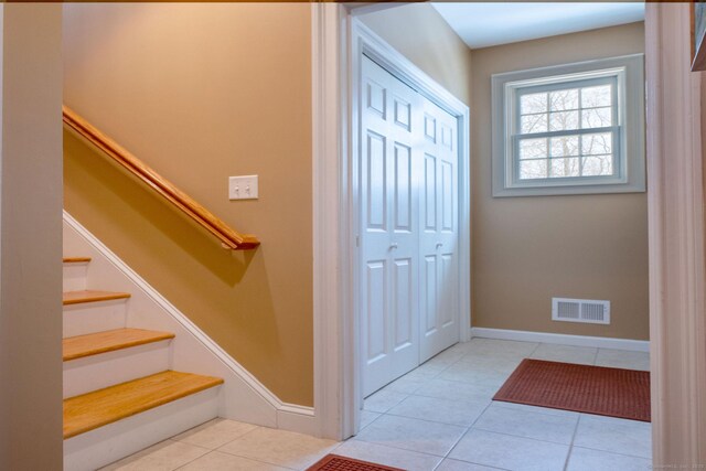 tiled foyer entrance featuring stairs, visible vents, and baseboards