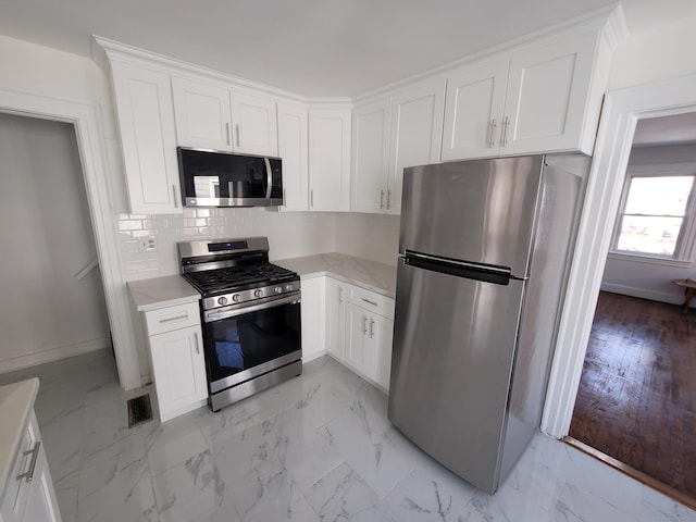 kitchen featuring appliances with stainless steel finishes, marble finish floor, light countertops, and white cabinetry