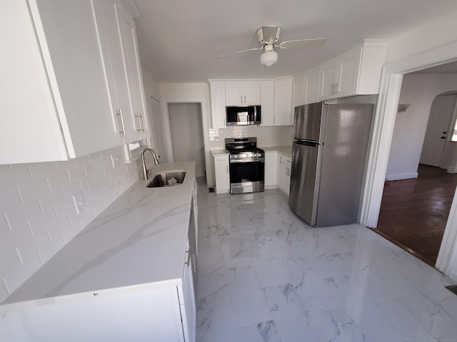 kitchen featuring appliances with stainless steel finishes, white cabinets, and a sink