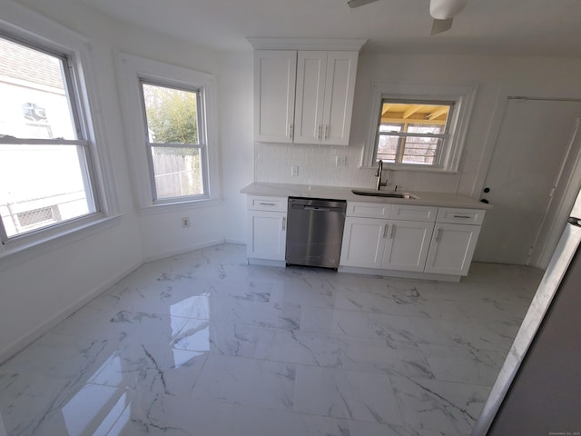 kitchen with marble finish floor, light countertops, stainless steel dishwasher, white cabinetry, and a sink