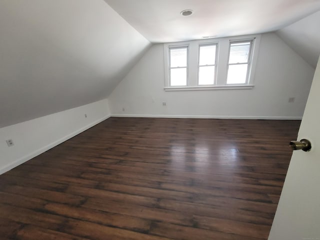 bonus room with vaulted ceiling, dark wood-style flooring, and baseboards