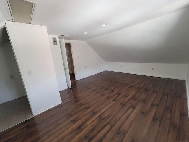 additional living space with dark wood-style floors, visible vents, vaulted ceiling, and baseboards