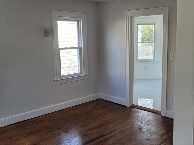 unfurnished room featuring dark wood-type flooring and baseboards