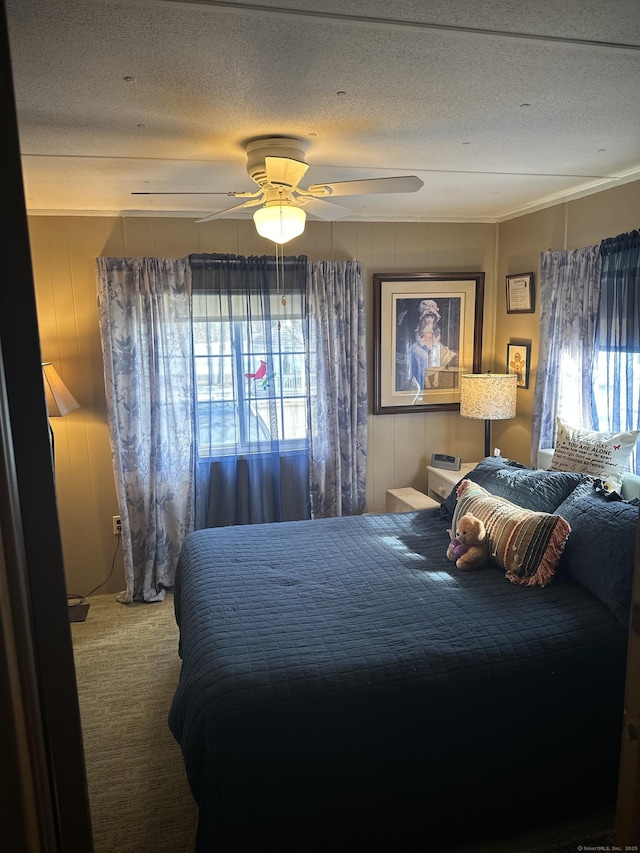 carpeted bedroom featuring a textured ceiling, a ceiling fan, and crown molding