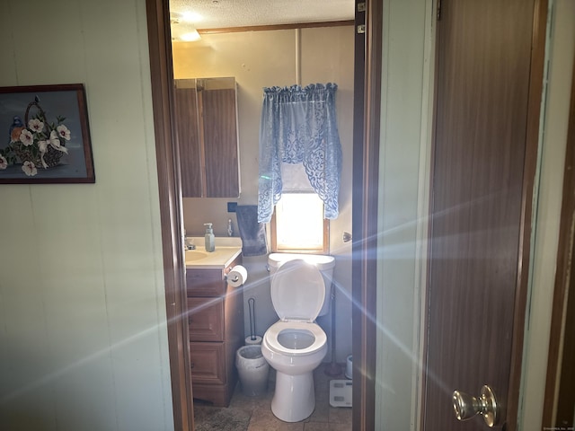 bathroom with a textured ceiling, tile patterned flooring, vanity, and toilet