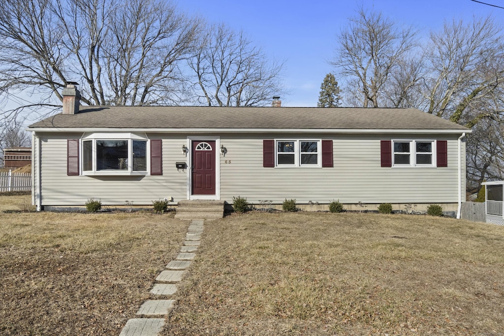 view of front of property with a front lawn, a chimney, a shingled roof, and fence