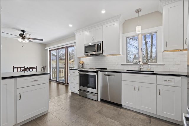 kitchen featuring stainless steel appliances, dark countertops, white cabinetry, and pendant lighting