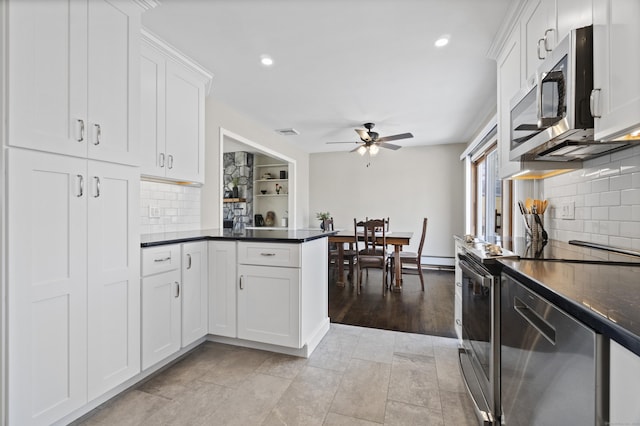 kitchen featuring appliances with stainless steel finishes, dark countertops, white cabinetry, and a peninsula