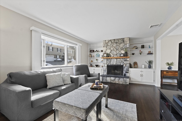 living room with dark wood-style floors, visible vents, a fireplace, and built in features