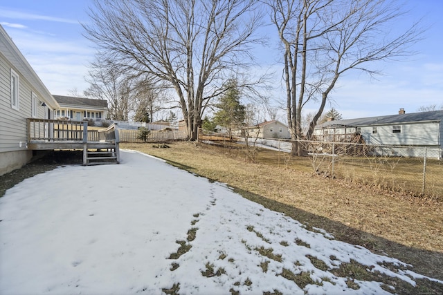 yard layered in snow with a fenced backyard and a deck