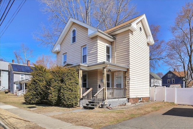 traditional-style house featuring a porch and fence