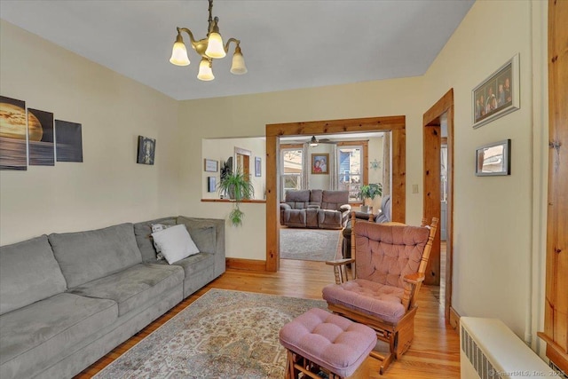 living room featuring light wood-type flooring, baseboards, radiator, and a chandelier