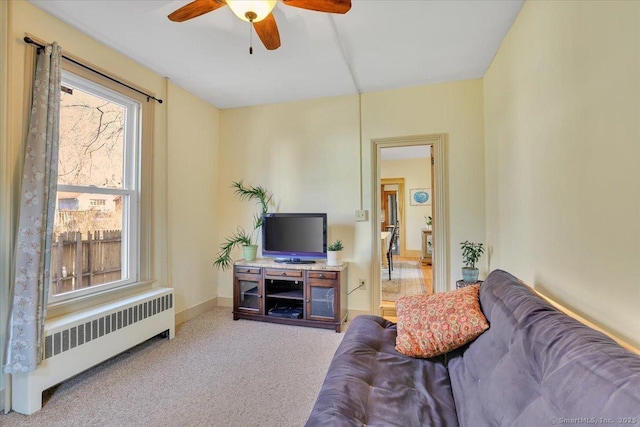 living room with ceiling fan, radiator, baseboards, and light carpet