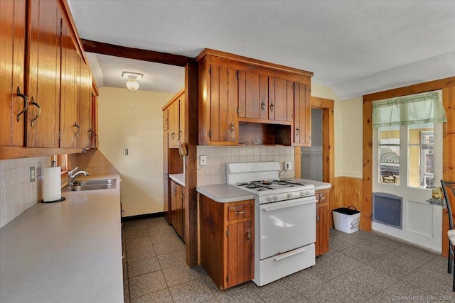 kitchen featuring light floors, white gas stove, a sink, vaulted ceiling, and light countertops