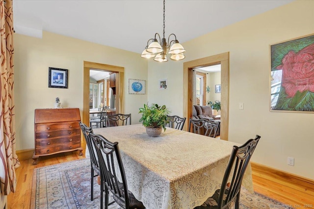 dining space featuring light wood-type flooring and a notable chandelier