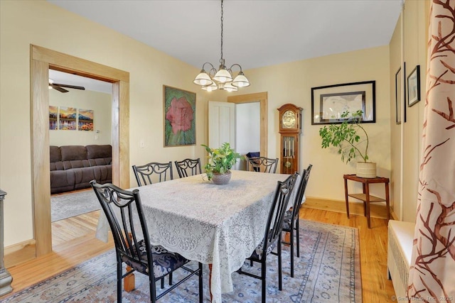 dining space featuring baseboards, a chandelier, and light wood finished floors