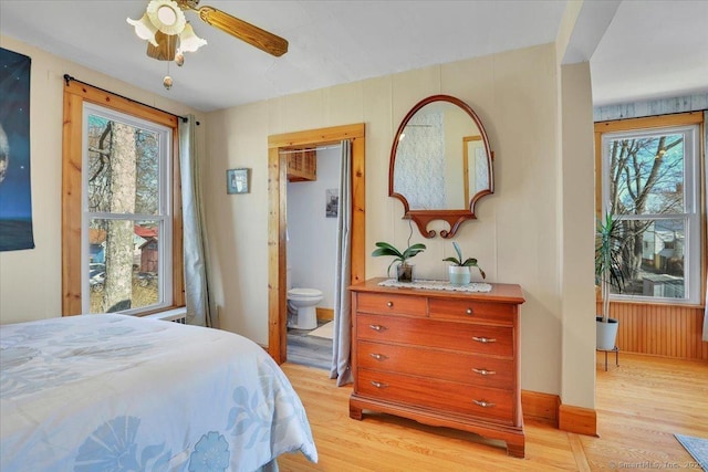 bedroom featuring baseboards, ensuite bathroom, and light wood-style floors