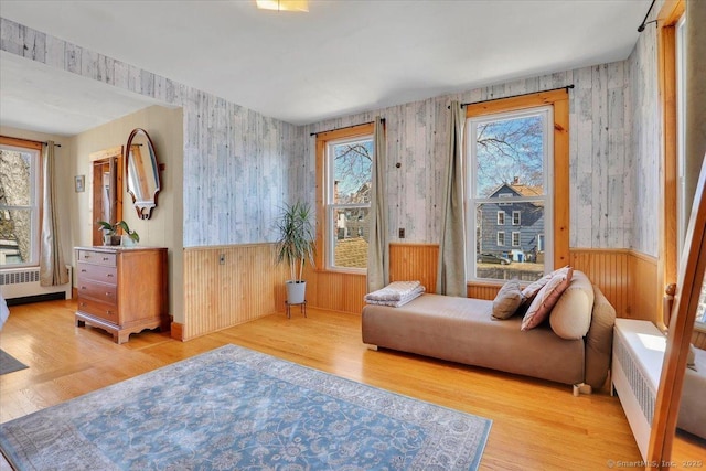 sitting room with a wainscoted wall, a healthy amount of sunlight, wood finished floors, and radiator heating unit