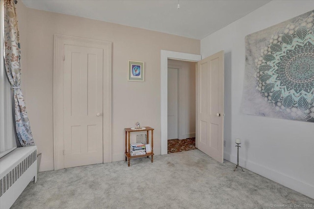 carpeted empty room featuring radiator heating unit